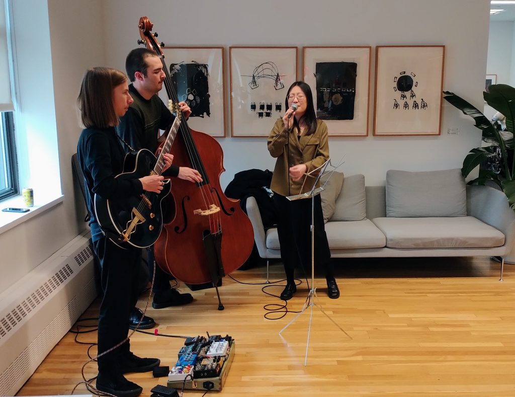 A trio of jazz performance students (singing, guitar and upright bass) perform at a staff party at the New School, May 4, 2023