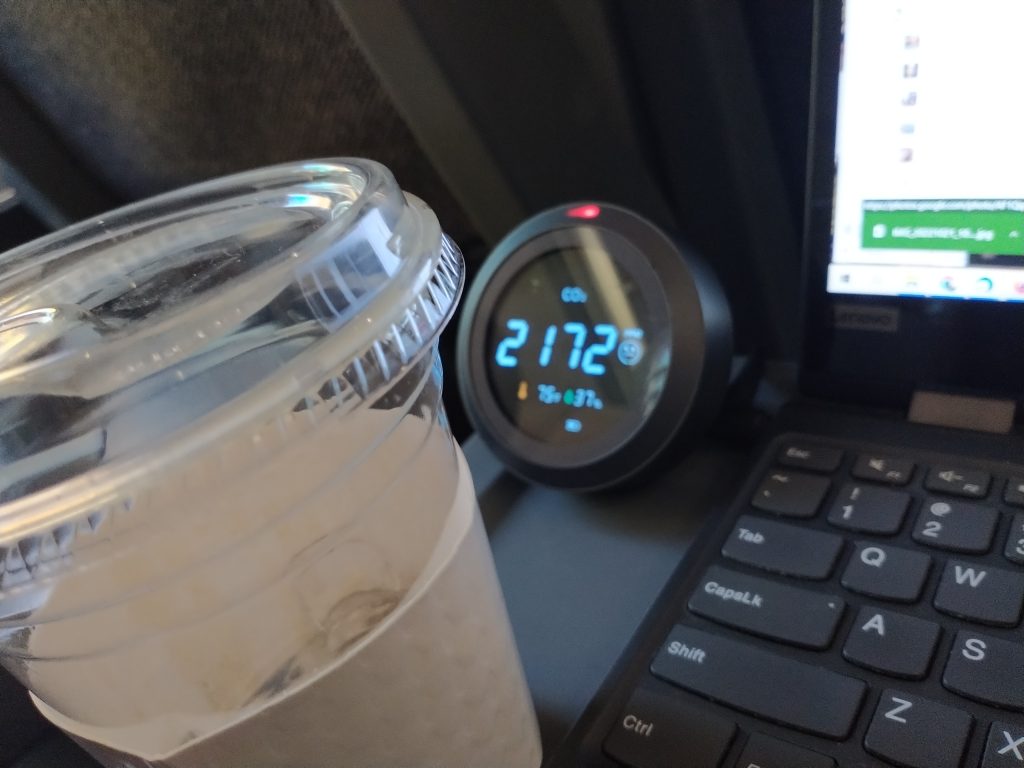 On the tray table in an Amtrak coach seat, a carbon dioxide monitor reads 2172 parts per million, 78 degrees Fahrenheit and 37% relative humidity